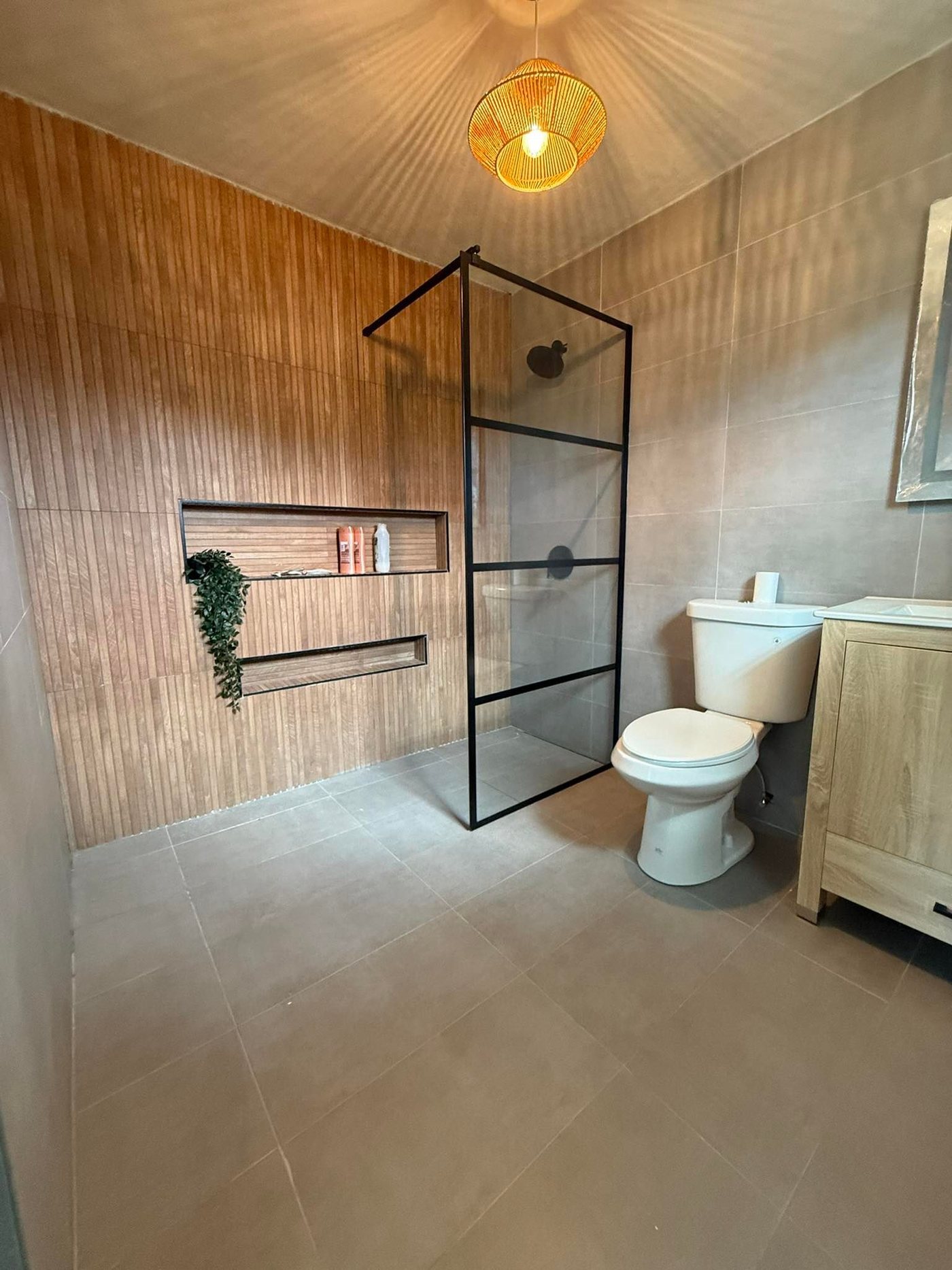 Modern bathroom with black-framed glass shower and slat accent wall